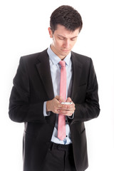 Smart young businessman typing message on his cell phone. He is wearing a suit and concentrating on what is on the screen