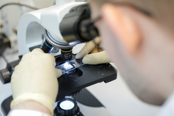 A laboratory assistant looks into microscope