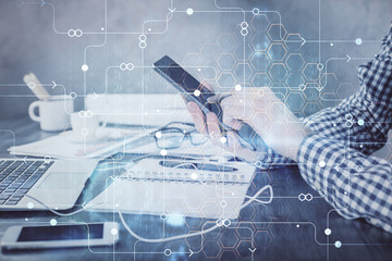 Double exposure of man's hand holding and using a digital device and data theme hologram drawing. Technology concept.