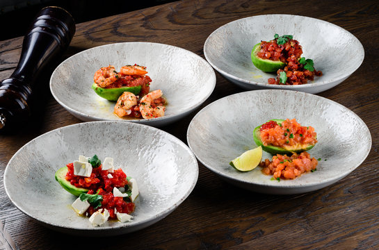 set of dishes with avocado, tartare and shrimp on a half avocado