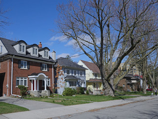 Residential street with large detached houses with front yards and mature trees