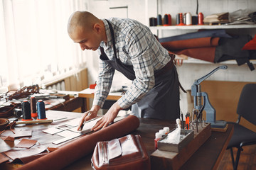 Man working with leather. Professional makes a wallet. erson measures the fabric.