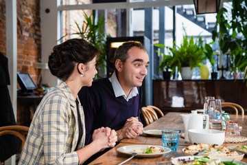 A couple chatting to someone at dinner in a cafe