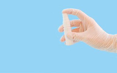 A female hand in a rubber white glove holds a bottle with an antiseptic for hands on a blue background. Banner.