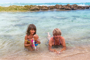 Young girl with grandmother along a beautiful tropical beach. Vacation and holiday concept