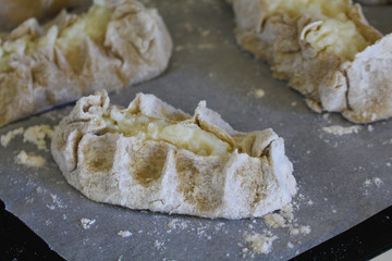 Stage of preparation of Karelian pies -Pirakka. Pies are located on a wooden board, being filled ready for baking. Dish of national cuisine - piirakka. Close-up.