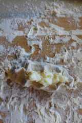 Stage of preparation of Karelian pies -Pirakka. Pies are located on a wooden board, being filled ready for baking. Dish of national cuisine - piirakka. Close-up.