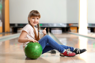 Fototapeta premium Little girl playing bowling in club