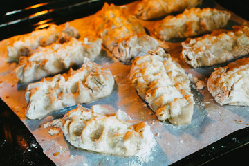 Stage of preparation of Karelian pies -Pirakka. Pies are located on a wooden board, being filled ready for baking. Dish of national cuisine - piirakka. Close-up.