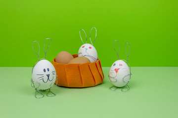Easter decorations on a green background. Eggs in rabbit stands. Color basket with Happy Bunny toys. The child painted the face of a rabbit.