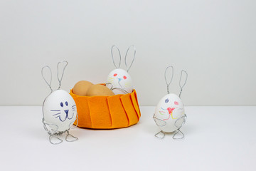 Easter decorations on a white background. Eggs in rabbit stands. Color basket with Happy Bunny...