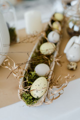 Home table decor. Festive table composition for traditional holiday dinner, decorated with moss and eggs. Happy easter concept