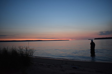 Silhouette person in lake at sunset 