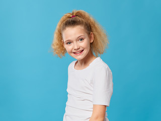 Fototapeta premium Cheerful girl curly hair white t-shirt smile blue background