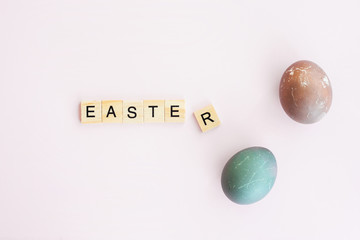 Collection of easter eggs. Word EASTER written on Scrubble letters isolated on pink background, flat lay.