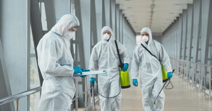 Team leader with notepad instructing workers with chemical detergents