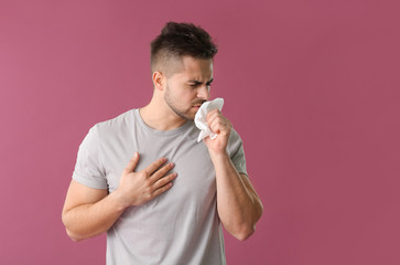 Coughing young man on color background