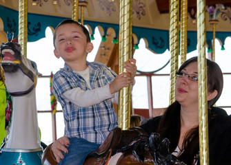 Indulgent parent  looks on while a  naughty  little boy makes a  mean face 