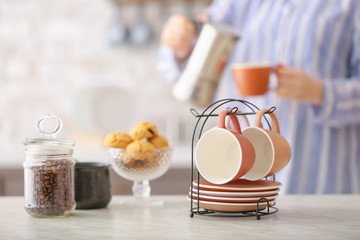 Holder with cups and saucers on table