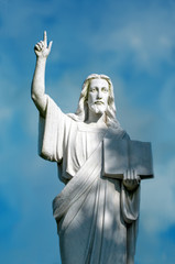 Fototapeta premium religious statue of Jesus holding a bible and pointing towards heaven