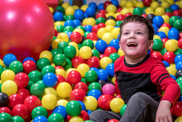 Fototapeta na wymiar laughing boy in a colorful ball pit at an indoor child play place