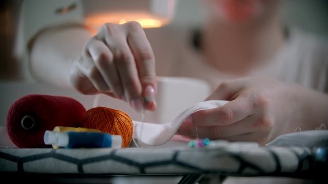 Young woman putting pins in the white cloth before sewing