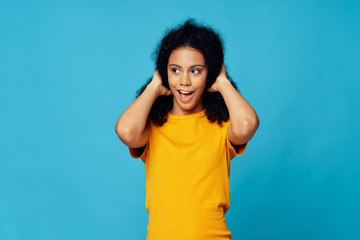Fototapeta premium Cheerful woman curly hair yellow t-shirt emotions smile blue background