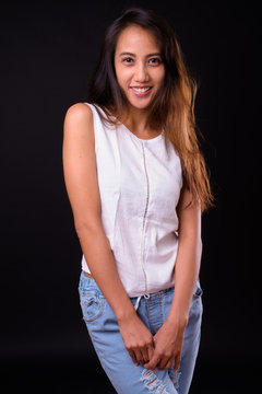 Young beautiful Asian woman against black background