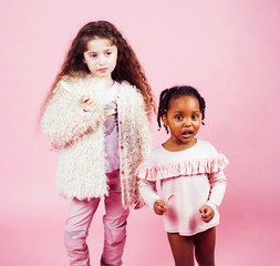 lifestyle people concept: diverse nation children playing together, caucasian and african american on pink background