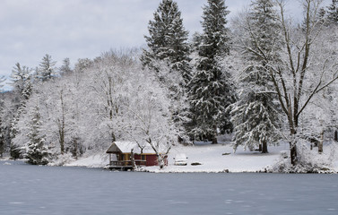 Winter landscape with a red cabin by the lake