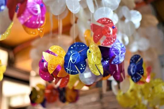 Colorful fish wind chimes made out of Capiz shells or windowpane oysters hang inside a shop