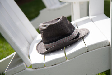 Fototapeta na wymiar Fedora hat on Adirondack lawn chair in sun