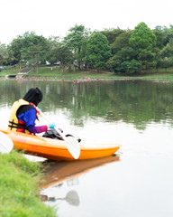 Fototapeta na wymiar Bangi, Malaysia - Oct 6, 2019: A woman in hijab is kayaking in the Taman Tasik Cempaka lake in the morning.
