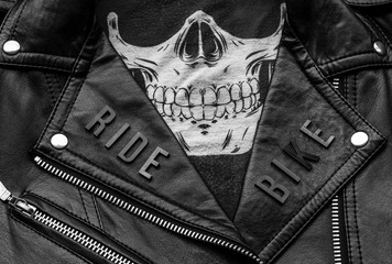 closeup to ride bike lettering over biker leather jacket and skull kerchief. motorcycle style, black and white photography