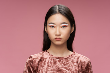 Beautiful woman of Asian appearance bright makeup studio luxury pink background model