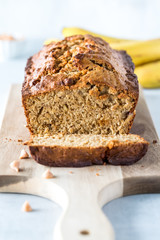 A straight on vertical view of a banana bread loaf that is sliced into with one slice in front.