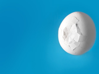white broken egg with cracks on a blue background