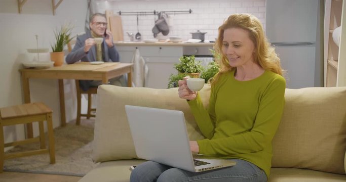 Middle-aged couple using modern technology at breakfast