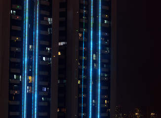 Manila/Philippines - April 10 2020: A night shot of a brightly lit residential building in Manila during the Corona Virus quarantine with city lights in the background.  