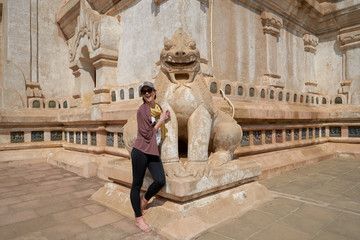 Fototapeta na wymiar Woman tourist and a sculpture of a guardian lion in the Ananda Temple, old Bagan, Myanmar, Burma. 