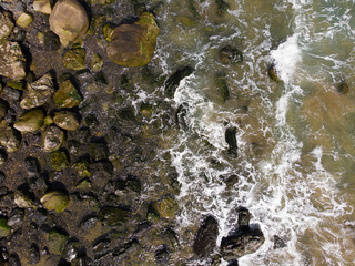 Stones on the beach with waves, ocean or sea. Texture, top view