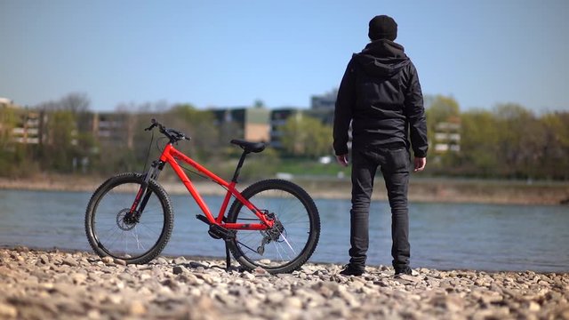 Cool Man / Athlete stands close to red Mountainbike MTB next to river / Outdoor - Fun - Action - Extreme Sports