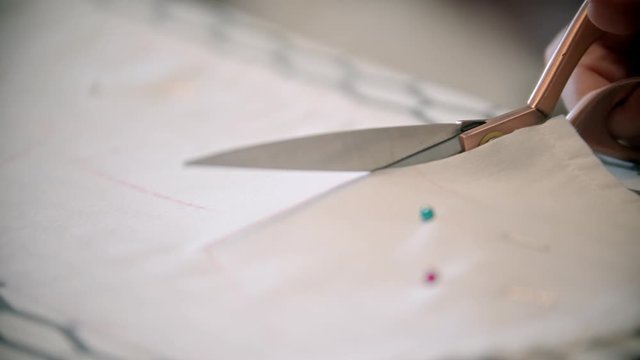 Young woman seamstress cutting the cloth following the soap mark