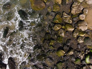 Stones on the beach with waves, ocean or sea. Texture, top view
