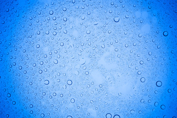 Rain droplets on blue glass background, Water drops on blue glass.