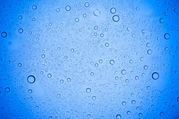 Rain droplets on blue glass background, Water drops on blue glass.
