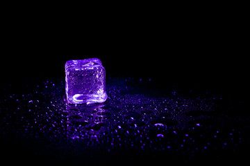 Purple ice cubes reflection on black table background.