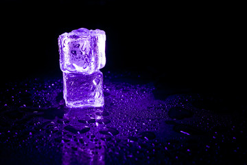 Purple ice cubes reflection on black table background.