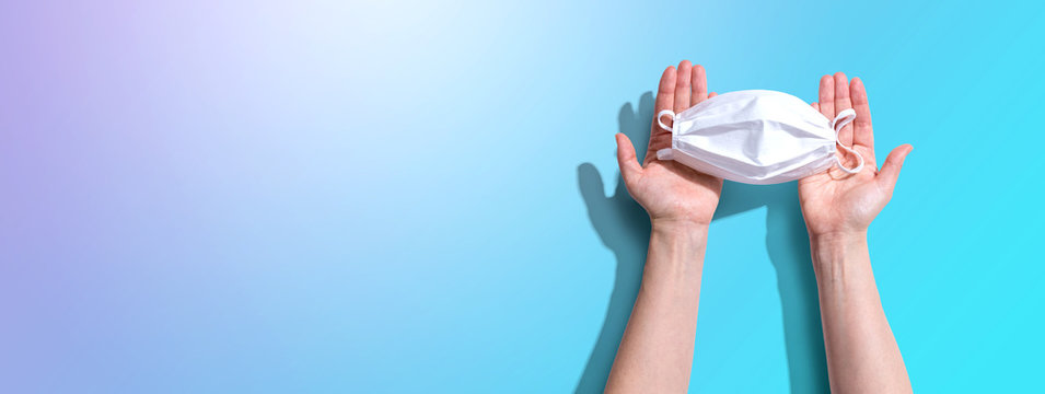 Person Holding A White Surgical Mask Overhead View - Flat Lay