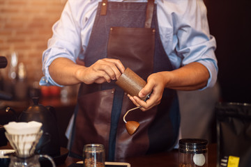 the barista hands on manual grinder coffee for grinding coffee beans at cafe.